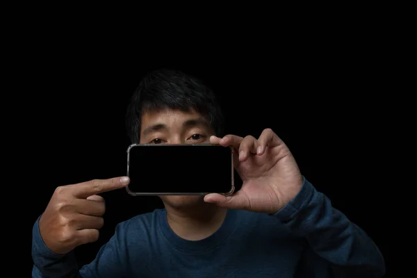 Young Man Holding Smartphone Pointing Finger Blank Screen Black Background — Stockfoto