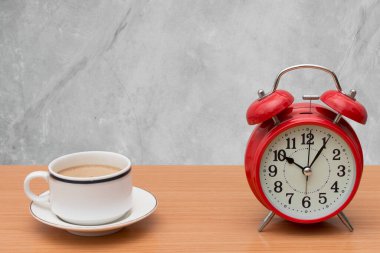Ahşap masa üzerinde çimento kaplı kahve ve çalar saat.