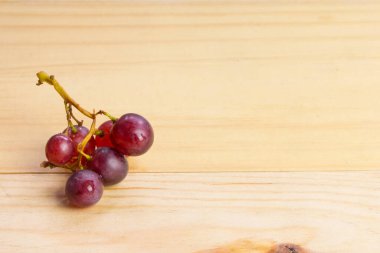 Tahta masada bir grup taze kırmızı üzüm.