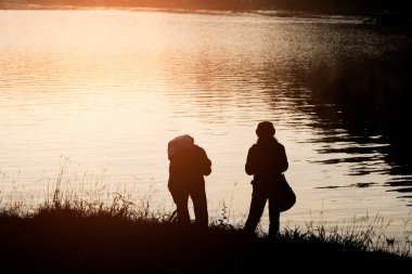 İnsanlar seyahat konsepti: Sabahları nehir kenarının güzel siluet manzarası
