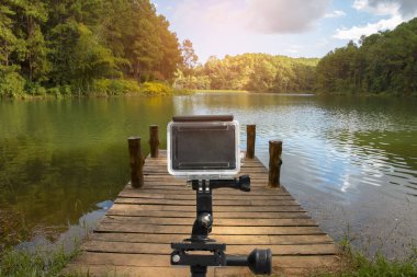 Gölün yanındaki ahşap rıhtımlı tripod üzerinde aksiyon kamerası.