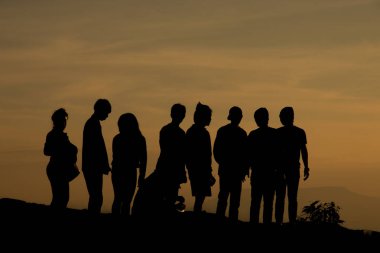İnsanların silueti kayalıklarda ve dağlarda dinleniyor akşamları günbatımında 