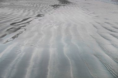 Sahildeki ıslak kumda dalgalanmaların dokusu 