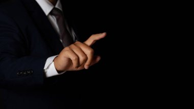Genç iş adamı siyah arka plana parmak işareti yapıyor. Boşluğu kopyala.
