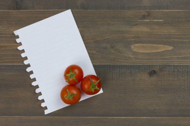 Yakın plan taze, olgun domatesler ve ahşap masa üzerinde beyaz kağıt.