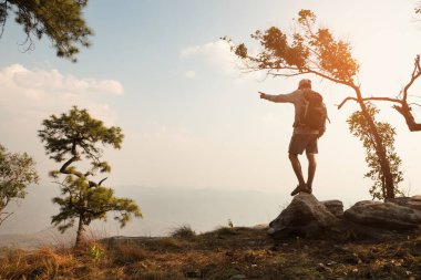 Uçurumda duran ve vadiye ve dağlara bakan bir adam.