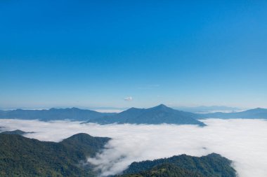 Vadideki uçurum ve gün ışığında sisli dağlar.