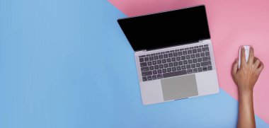 Person using a laptop computer from above on pink and blue background. free text copy space. top view.