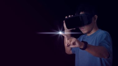 Man wearing VR Headset touching something by his fingers on neon color background. Glasses of virtual reality and exploring the metaverse. Technology, gaming, entertainment and people concept.