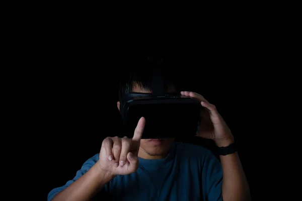 Studio portrait man wearing VR Headset touching something by his fingers on black background. Glasses of virtual reality. Technology, gaming, entertainment and people concept.