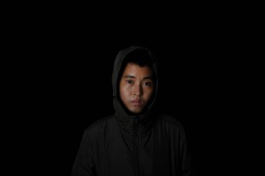 Man wear overcoat with hood on head on black background. Concept of fashion and stylish male. Free text copy space.
