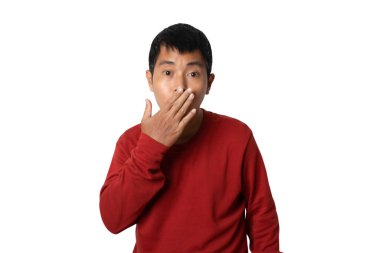 Portrait of young man wearing casual t-shirt covering mouth by hand. Shocked and surprised. Human emotion face expression concept. studio shot isolated on white background. copy space.