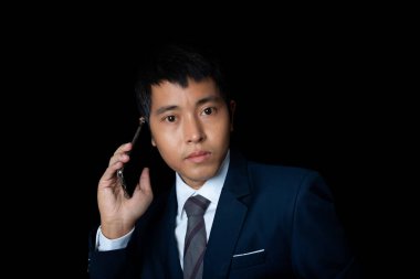 Portrait of businessman talking smartphone. Human emotion face expression concept. Studio shot on black background. copy space