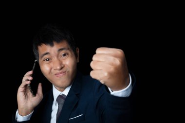 Portrait of businessman talking smartphone with winner gesture and celebrating victory happy. Human emotion face expression concept. Studio shot on black background. copy space.