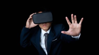 Studio portrait businessman wearing VR Headset touching something isolated on black background. Glasses of virtual reality. Technology, gaming, entertainment and people concept. copy space.