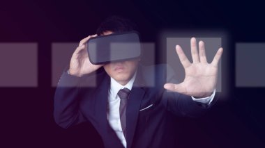 Man wearing VR Headset touching on a touch screen interface on neon color background. Glasses of virtual reality and exploring the metaverse. Technology, gaming, entertainment and people concept.