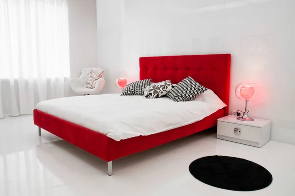 White room med en röd säng Stockfoto