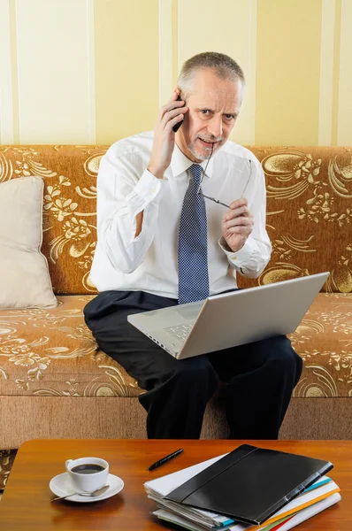 Homme d'affaires senior travaillant avec ordinateur et smartphone — Photo