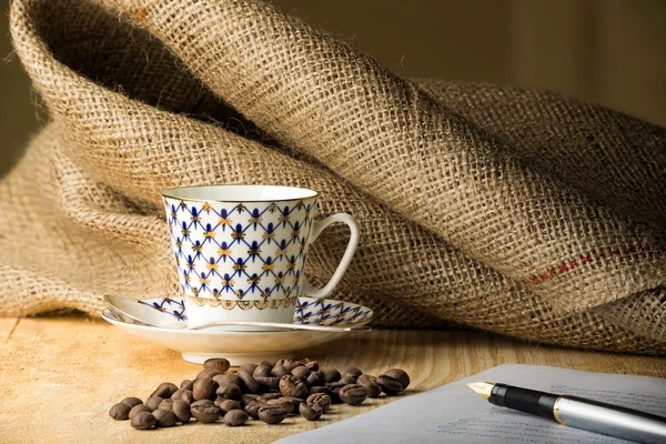 Granos de café con taza y pluma —  Fotos de Stock