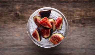 Sağlıklı chia pudingi. Kırsal arka planda incir parçaları var. Seçici odaklanma. Sığ alan derinliği.