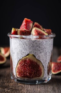 Sağlıklı chia pudingi. Kırsal arka planda incir parçaları var. Seçici odaklanma. Sığ alan derinliği.