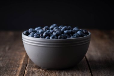 Kırsal ahşap arka planda seramik kasede yabanmersini. Seçici odaklanma. Sığ alan derinliği.