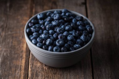 Kırsal ahşap arka planda seramik kasede yabanmersini. Seçici odaklanma. Sığ alan derinliği.