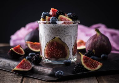 Sağlıklı chia pudingi. Kırsal arka planda incir ve koyu renkli böğürtlen. Seçici odaklanma. Sığ alan derinliği.