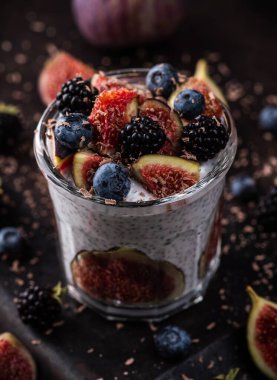 Sağlıklı chia pudingi. Kırsal arka planda incir ve koyu renkli böğürtlen. Seçici odaklanma. Sığ alan derinliği.