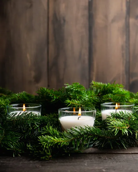 Lighted candle in the green pine branches. Christmas background. Selective focus.