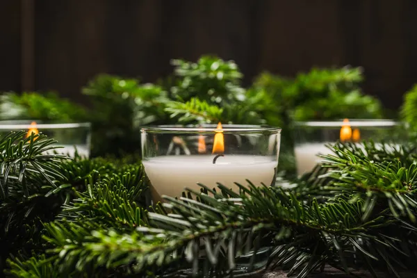 Lighted candle in the green pine branches. Christmas background. Selective focus.