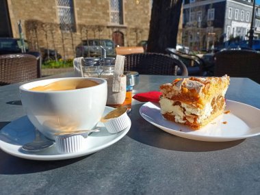 Terasta bir fincan kahve ve kremalı pasta.