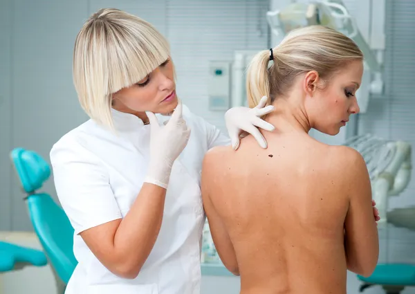 Läkaren inspekterar kvinna patientens hud — Stockfoto