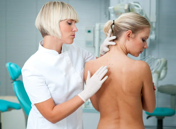 Lekarz kontrolujący kobieta skóry pacjenta — Zdjęcie stockowe