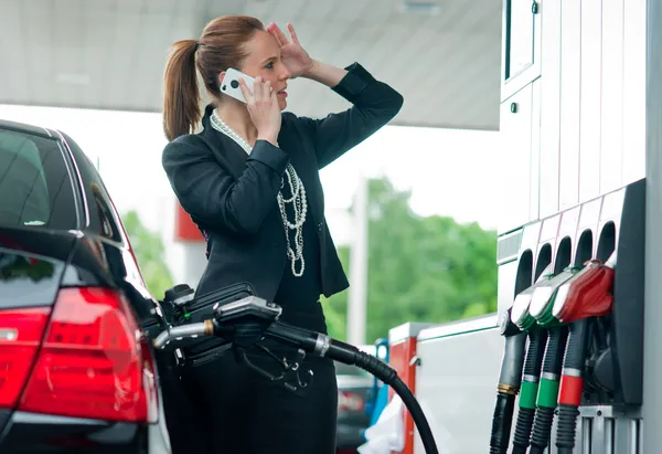 Mulher no posto de gasolina falando com o telefone móvel — Fotografia de Stock