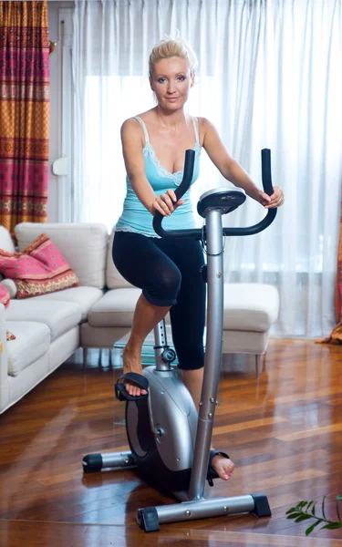 Vrouw op stationaire fiets Stockfoto