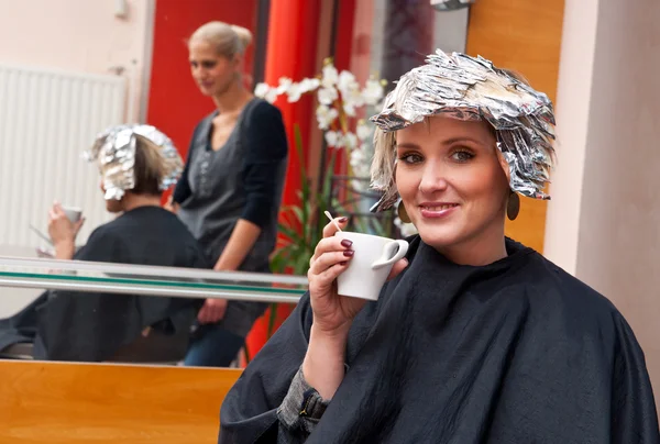 Mulher relaxante sobre café no salão de cabeleireiro Imagem De Stock