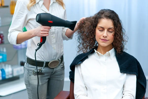 Стилист сушит женские волосы в салоне — стоковое фото