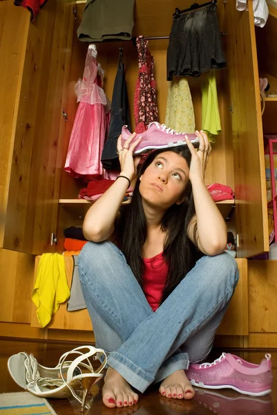 Confused girl in front of open closet Stock Picture