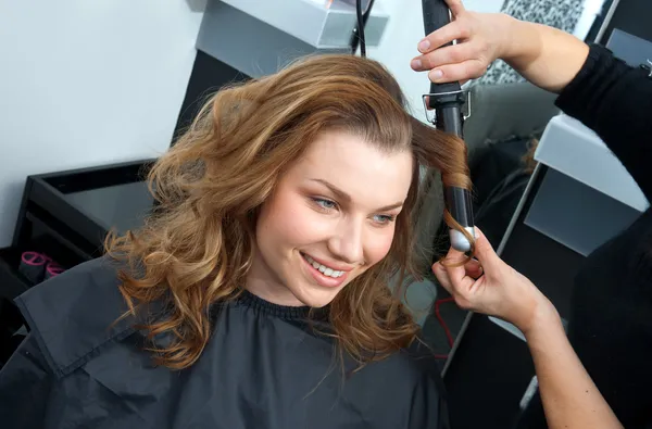 Frau kräuselt Haare im Friseursalon — Stockfoto