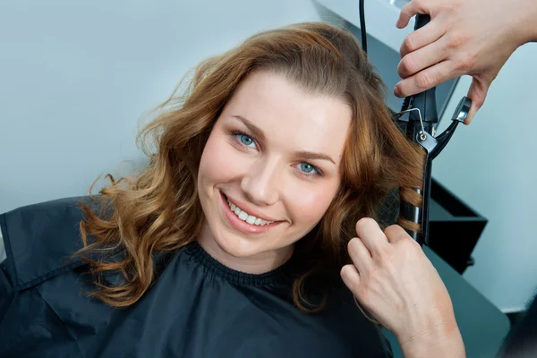 Woman curling hair in hairsalon Stock Image