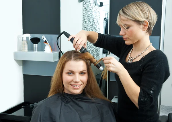 Hair stylist curling woman hair in salon Royalty Free Stock Images
