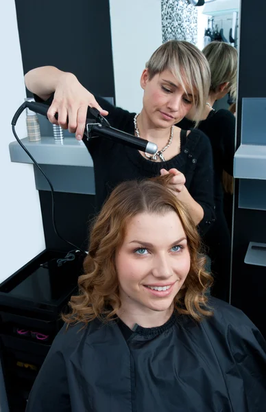 Hair stylist curling woman hair Stock Photo