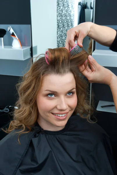 Hair stylist curling woman hair in salon Royalty Free Stock Photos