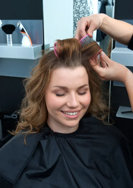Hair stylist curling woman hair in salon Royalty Free Stock Images