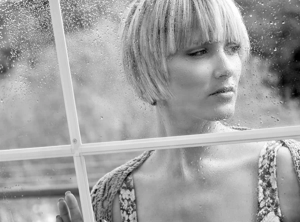 Грустная женщина у окна — стоковое фото