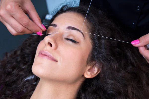 Kvinna på ansikts hårborttagning threading förfarande — Stockfoto