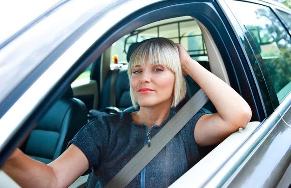 Aantrekkelijke vrouw zitten in haar auto — Stockfoto