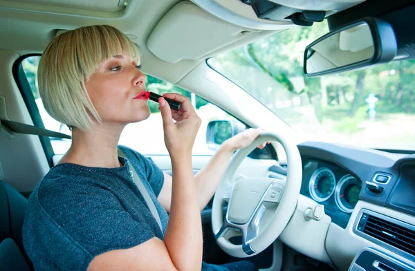 Attractive woman applying make up in her car Stock Picture