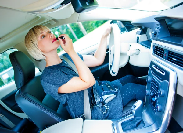 Aantrekkelijke vrouw toepassing maken omhoog in haar auto Stockfoto